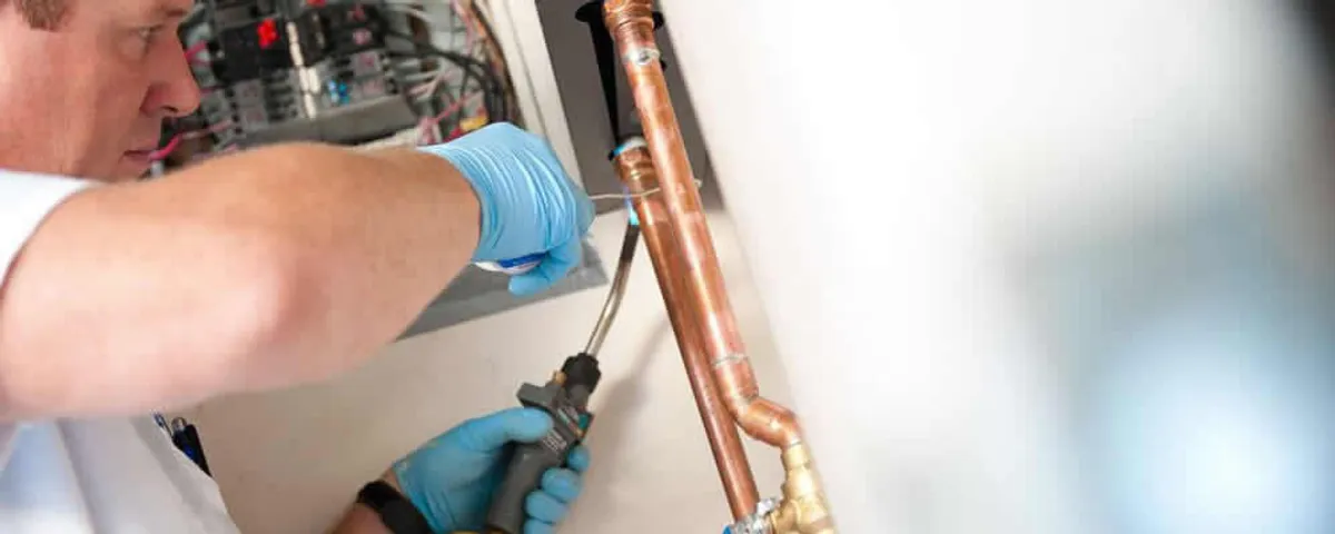 Water heater repair technician testing copper pipe connections and controls in Flagstaff, AZ